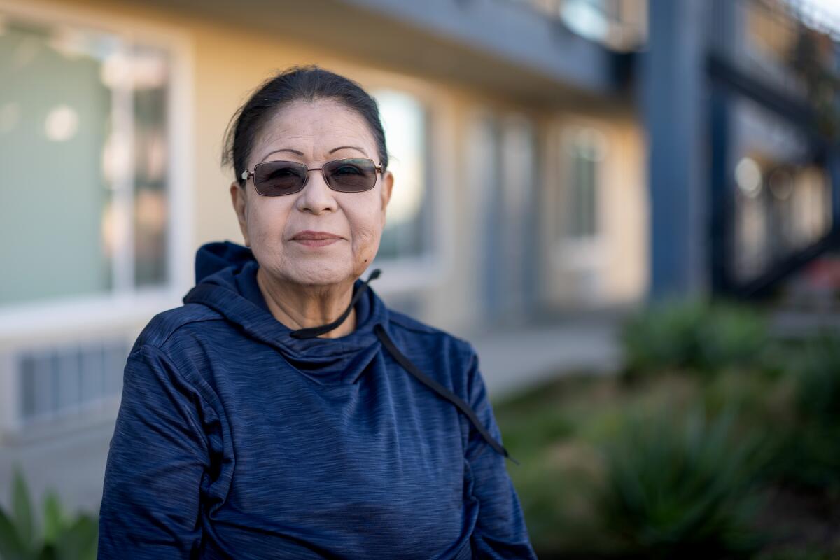 a woman poses for a portrait wearing sunglasses and a blue shirt