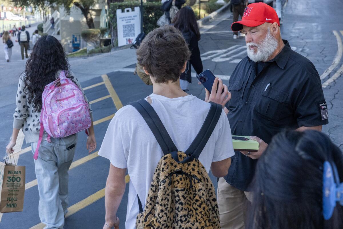 A school security guard looks at a cellphone. 