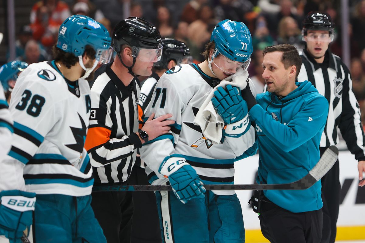 #71 C Macklin Celebrini of the San Jose Sharks is helped off the ice after an injury in the third period during an NHL game against the Anaheim Ducks on December 29, 2025 in Anaheim, CA.