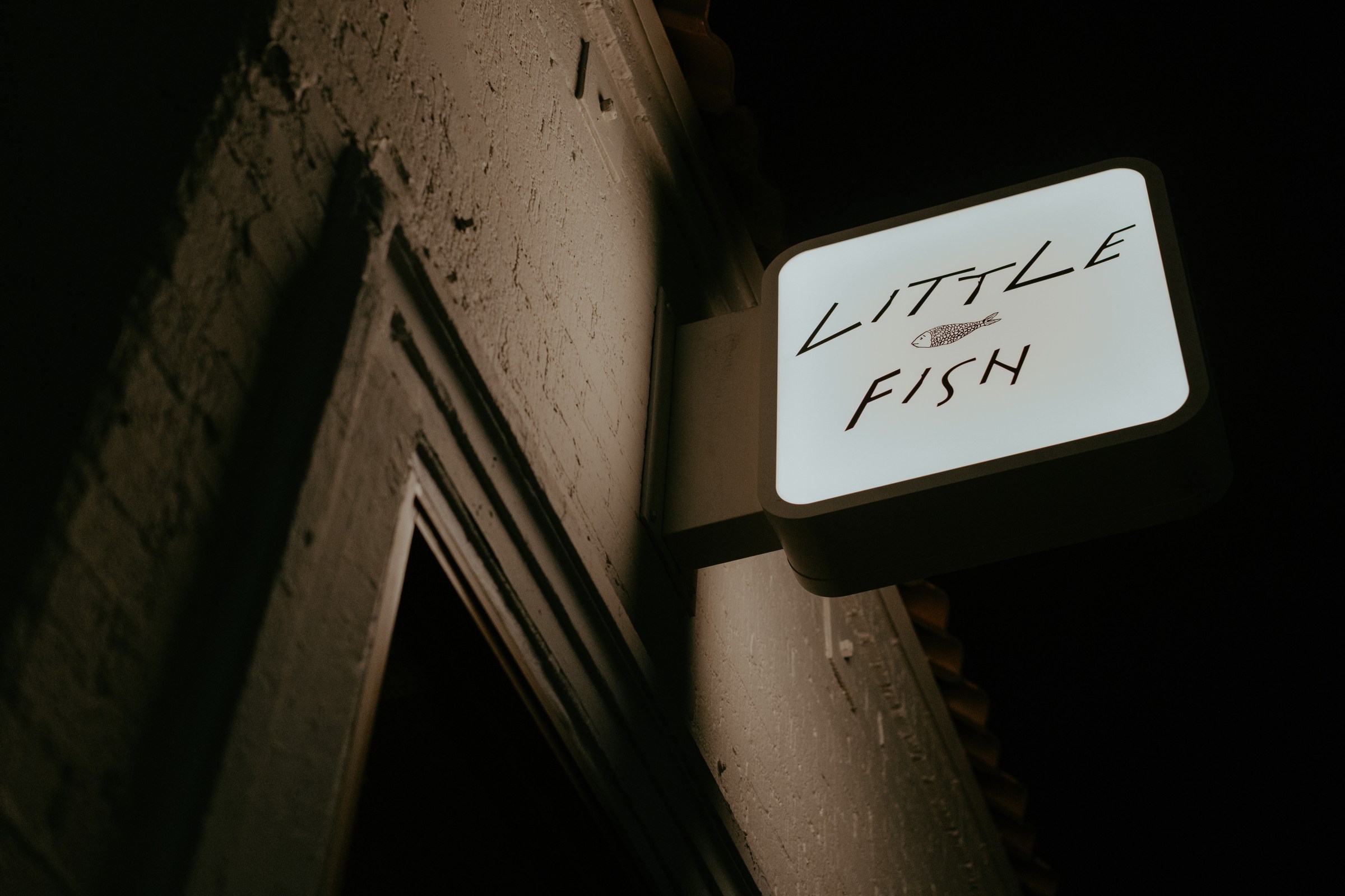 Lit-up Little Fish sign outside at night.