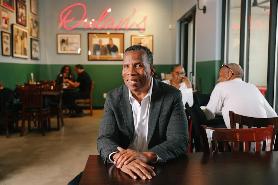 A man seated at a table smiles for the camera.