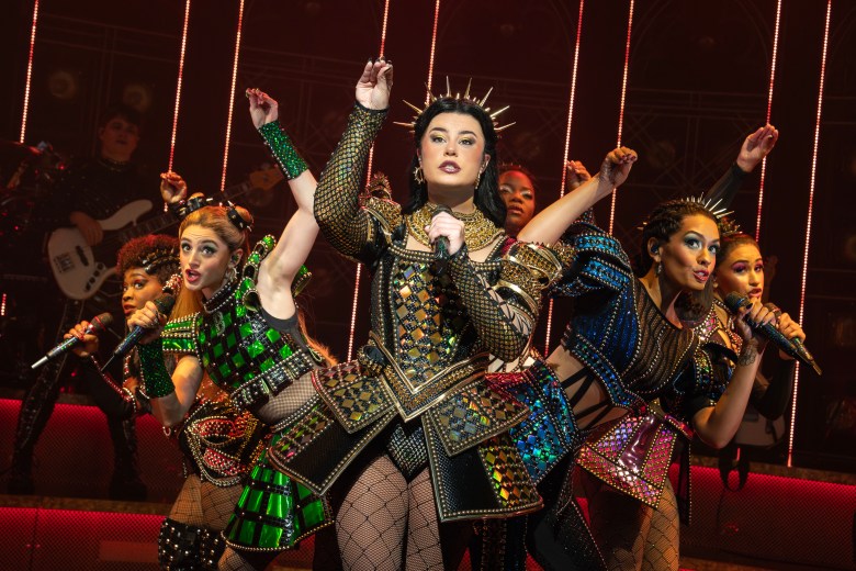 Stylized pop queens fan out behind a singer in a gold outfit. 