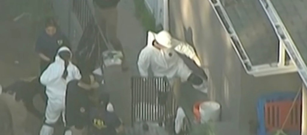 An aerial view shows investigators in white hazmat suits and a police officer working at a crime scene.