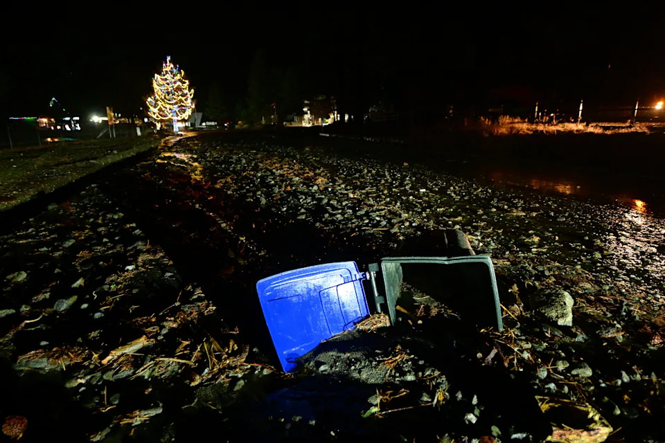 A trashcan lies stuck in mud on California State Route 2 after flooding Wednesday, Dec. 24, 2025, in Wrightwood, Calif.