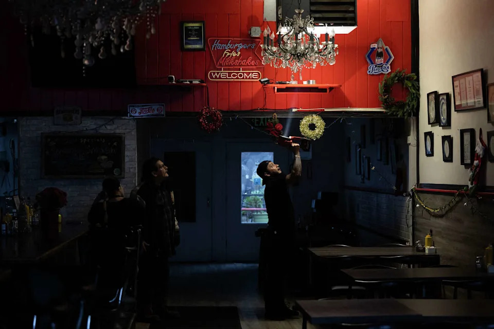 Aristides Rodriguez, an employee at Bill's Place, holds a flashlight during Saturday's power outage in San Francisco. (Benjamin Fanjoy/For the S.F. Chronicle)