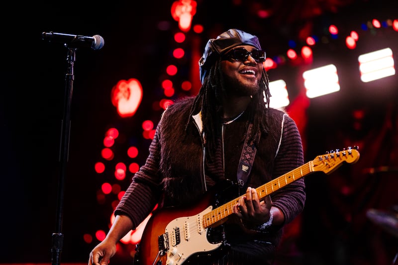Leon Thomas on-stage in all Black attire with guitar