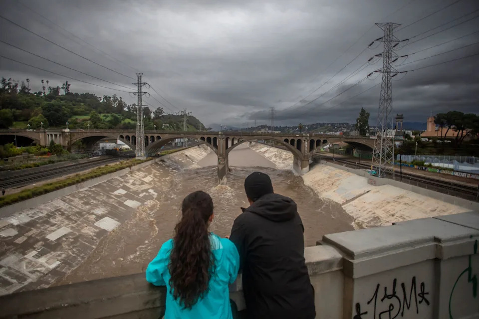 A couple watches the high water level of the Los Angeles river after heavy rains on Dec. 24.