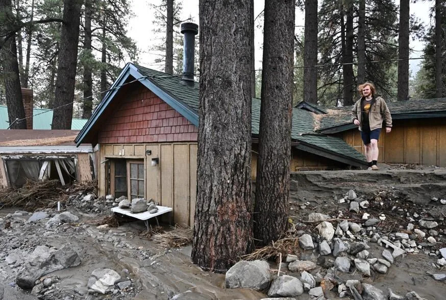 Davey Schneider walks on the roof of his storm-damaged home on Dec. 25, 2025, in Wrightwood, Calif. / Credit: William Liang / AP