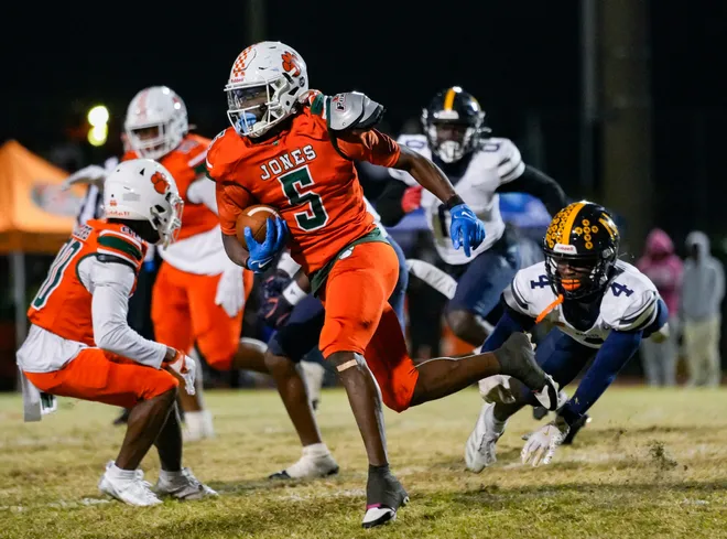 Jones Fightin' Tigers running back Jaquail Smith (5) runs the ball past Naples Golden Eagles defensive back Xavian Michel (4) during the fourth quarter of the Class 4A state semifinal at Jones High School in Orlando, Fla., on Friday, Dec. 6, 2024.