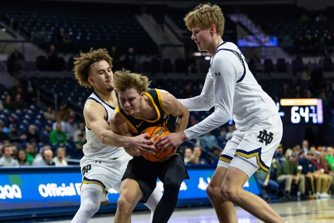 Dec 10, 2025; South Bend, Indiana, USA; Idaho Vandals guard Kolton Mitchell (14) tries to drive between Notre Dame Fighting Irish guard Braeden Shrewsberry, left, and forward Brady Koehler, right, during the second half at Purcell Pavilion at the Joyce Center.