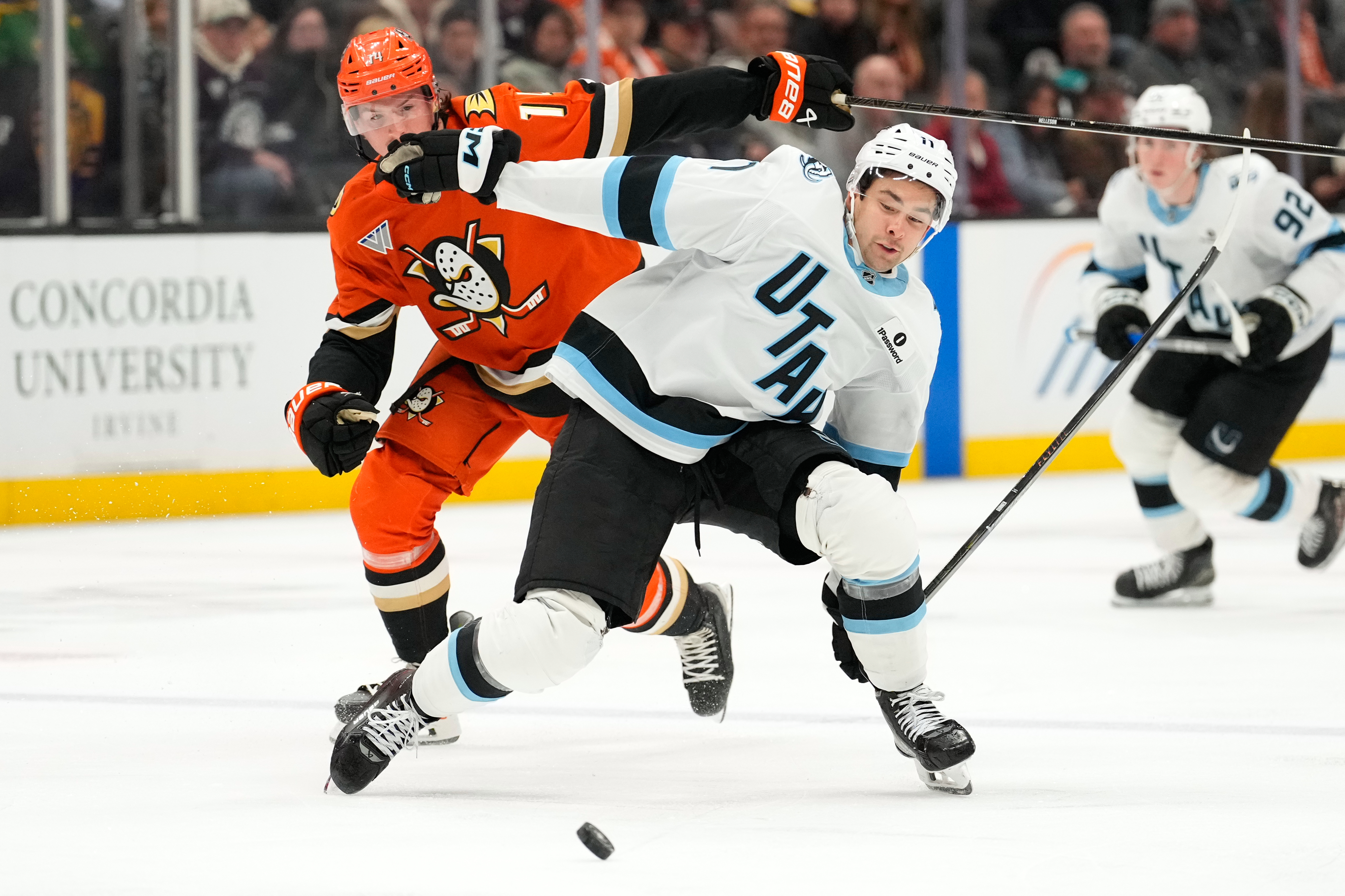 Ducks defenseman Drew Helleson, left, and Utah Mammoth right wing...