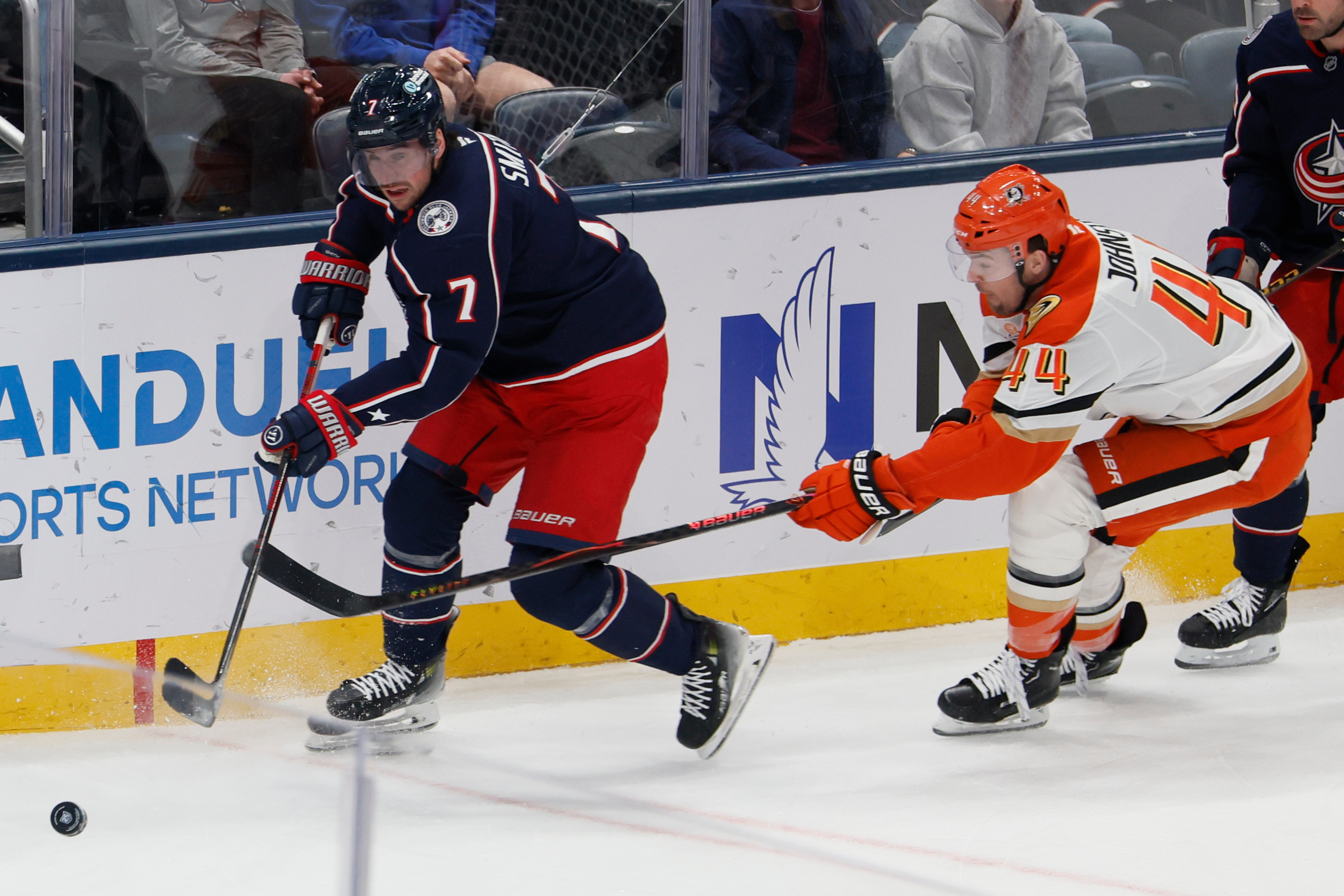 The Columbus Blue Jackets’ Brendan Smith, left, clears the puck...