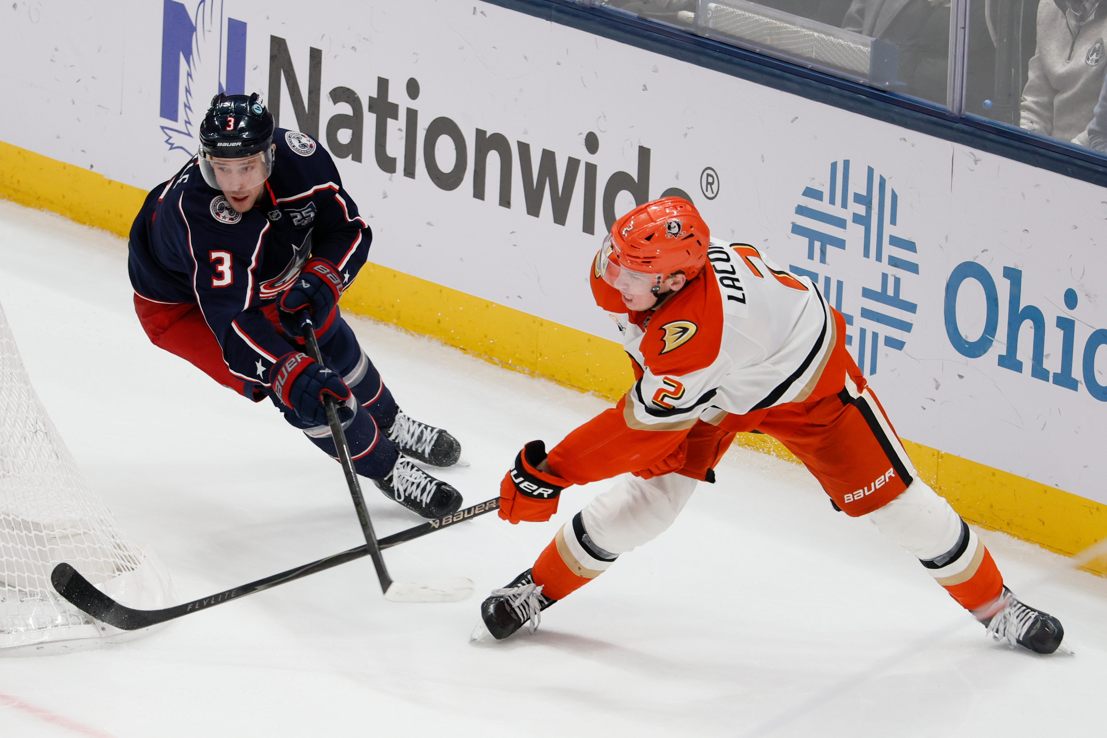The Ducks’ Jackson LaCombe, right, passes the puck as the...