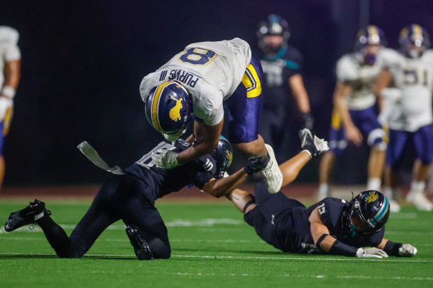 Lincoln's Jaymes Purvis III (8) jumps with the ball over Valley Center's Gauge Wright (10) and Valley Center's Joaquin Stehly (12) in the fourth quarter during Division 6-AA state football championship game at Fullerton Union High School District Stadium in Fullerton, Calif., on Friday, Dec. 12, 2025. (Shae Hammond/Bay Area News Group)