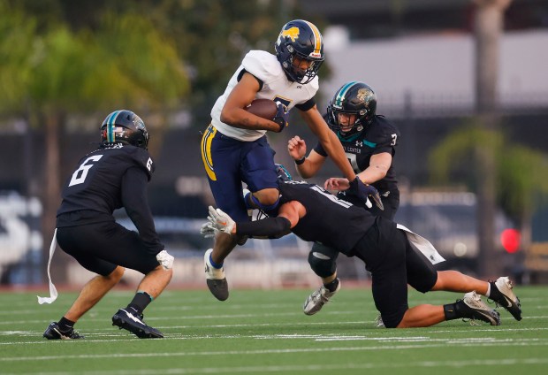 Lincoln's Michael Whitelaw (7) jumps with the ball against Valley Center's Jesse Morales (6) and Valley Center's Joaquin Stehly (12) in the second quarter during Division 6-AA state football championship game at Fullerton Union High School District Stadium in Fullerton, Calif., on Friday, Dec. 12, 2025. (Shae Hammond/Bay Area News Group)
