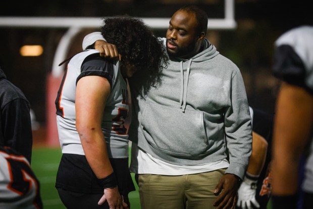 McClymonds' Koi Taiese (51) rest his head on his coach's shoulder after losing against Kennedy-Delano during the Division 3-A state championship football game at Fullerton Union High School District Stadium in Fullerton, Calif., on Saturday, Dec. 13, 2025. (Shae Hammond/Bay Area News Group)