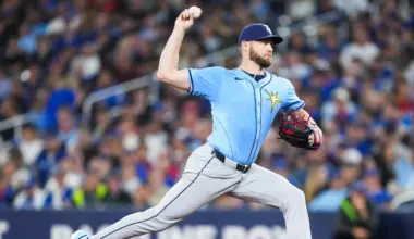 A football player in a red and gold uniform, holding a football, runs on a grassy field with a blurred crowd in the background.