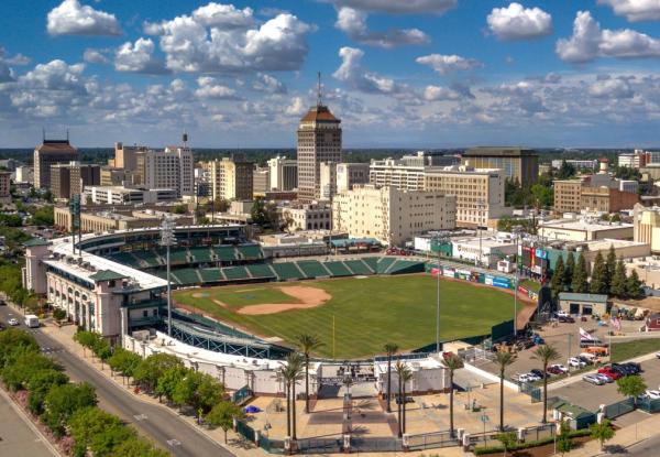 Baseball stadium with blue sky and white clouds and city skyline in background