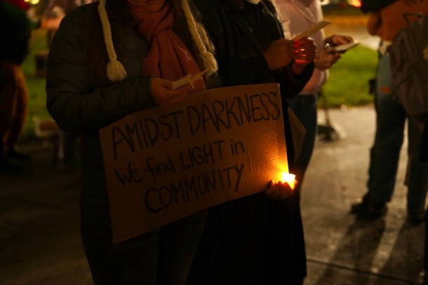 A memorial attendee carries a sign expressing communal resolve. Neenma Ebeledike, OBSERVER