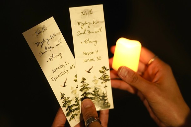 A mourner holds two memorial cards featuring names of deceased unhoused people. The cards were distributed at the 13th annual Memorial and Candlelight Vigil for the Unhoused. Neenma Ebeledike, OBSERVER
