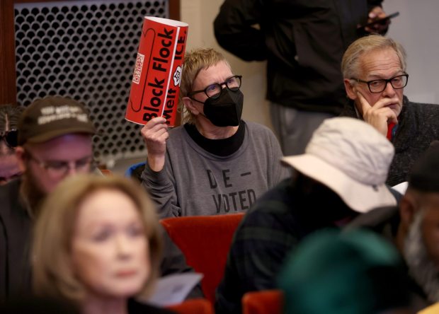 A community member displays a sign during an Oakland City Council meeting at City Hall in Oakland, Calif., on Tuesday, Dec. 16, 2025. The Oakland City Council voted 7-1 to award Flock Safety a new contract to maintain an existing network of 300 cameras in the city. (Jane Tyska/Bay Area News Group)