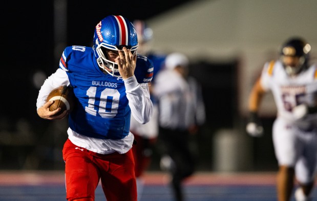 Folsom Bulldogs quarterback Brody Rudnicki (10) adjusts his loose helmet as he rushes down the sideline for 50 yards against the Riordan Crusaders in a CIF Northern California Regional Division 1-AA football championship game in Folsom on Friday, Dec. 5, 2025. (Nathaniel Levine/The Sacramento Bee)