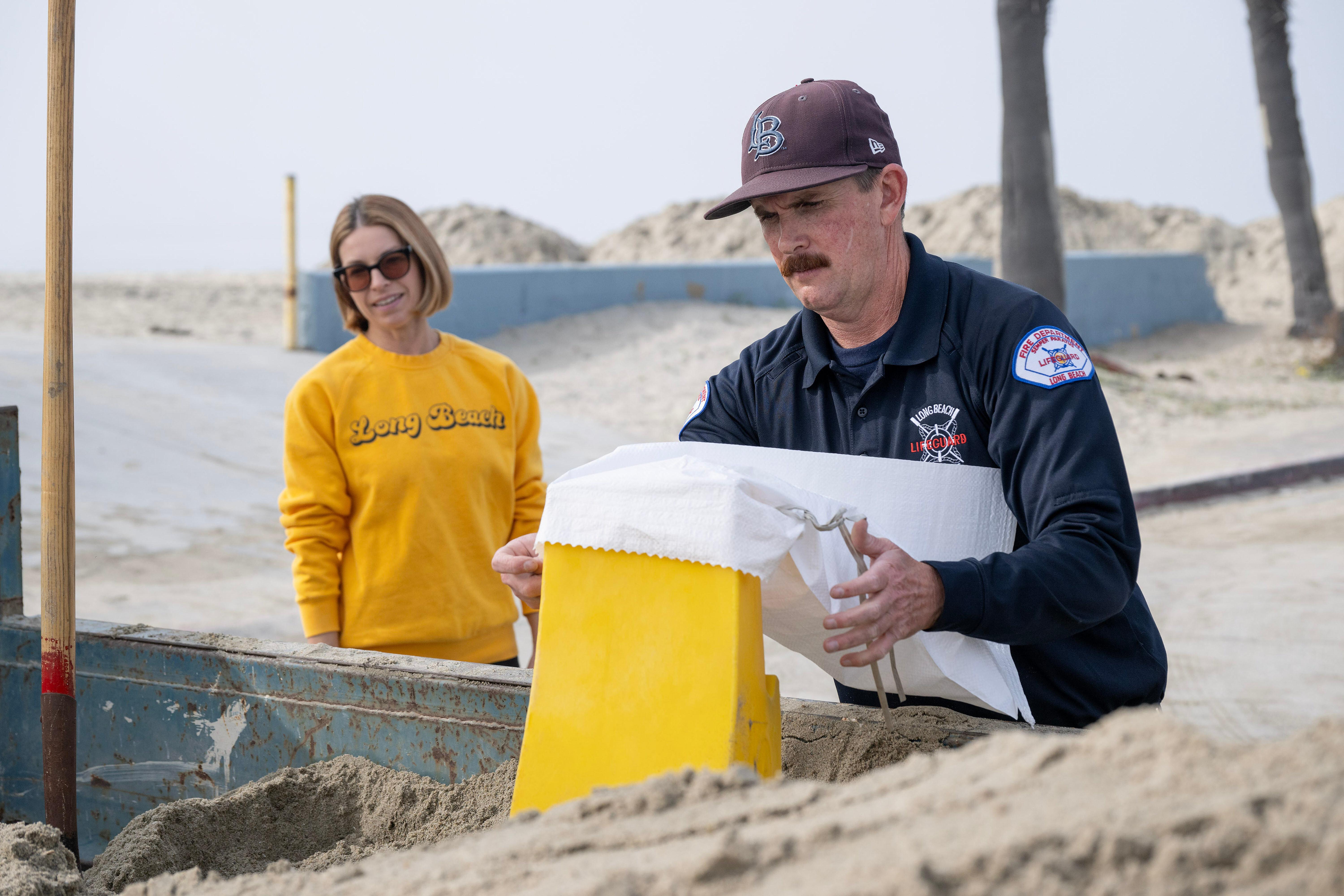 From right, Ocean Lifeguard Sean Guerin prepares sandbags for Kim...