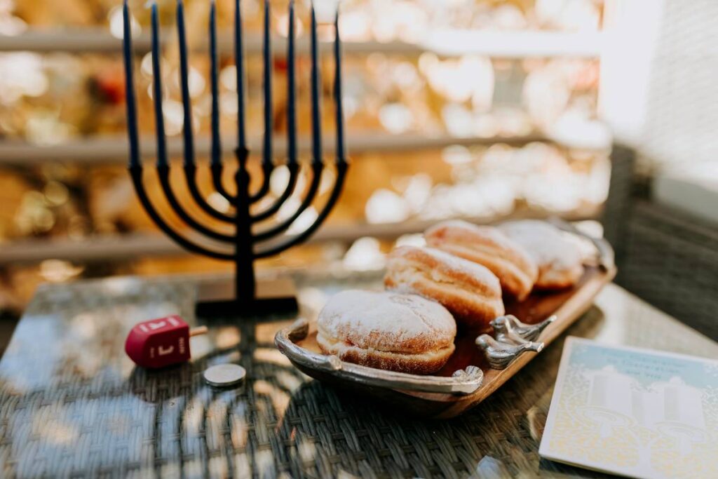 A menorah, dreidel, and sufganiyot displayed on a table for Hanukkah.