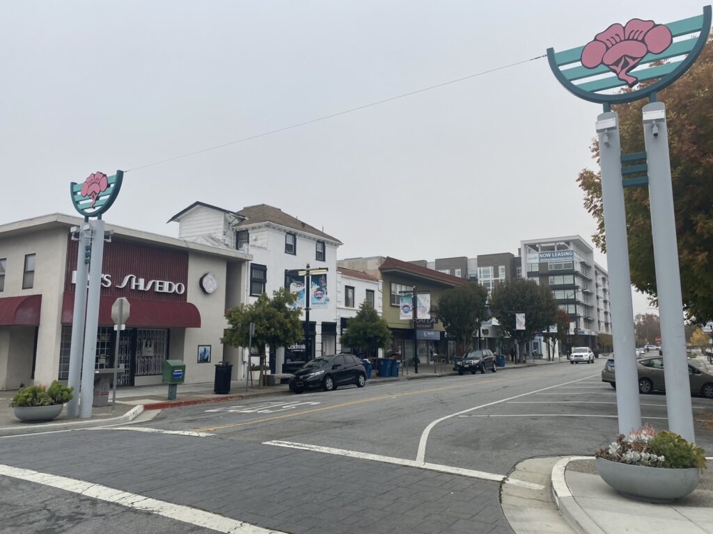 Colorful pilers flank a roadway lined by trees and small commercial buildings.