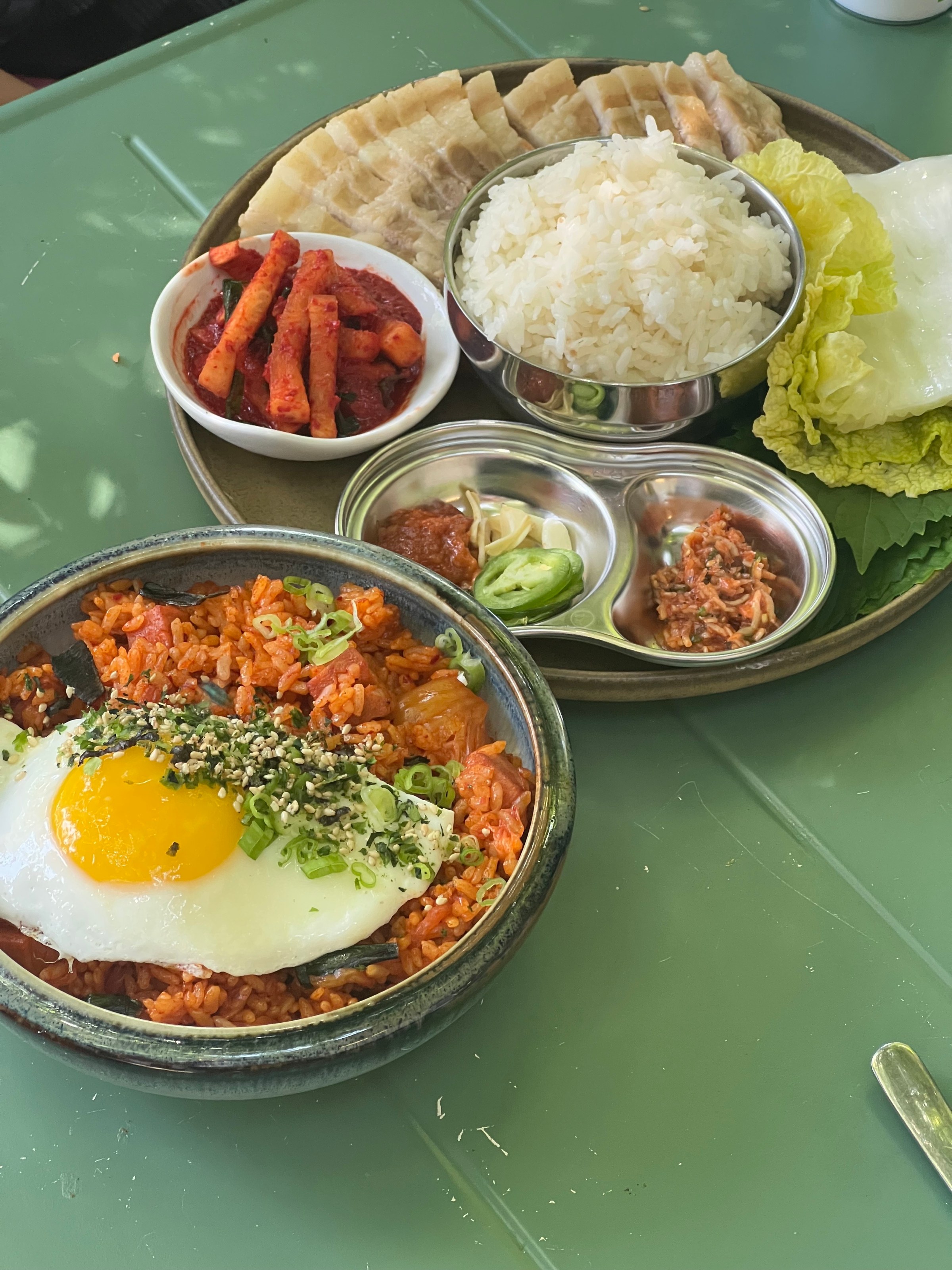 Kimchi fried rice with a sidecar of banchan, leafy greens, meat, and rice on a tray. 