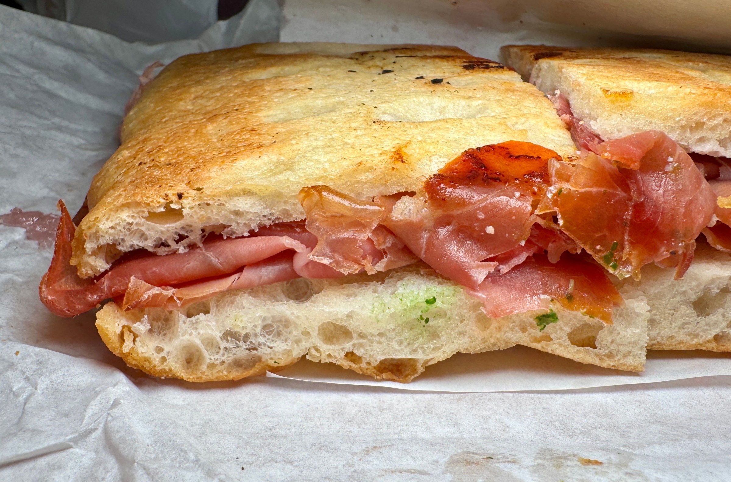 Focaccia sandwich with prosciutto on parchment paper