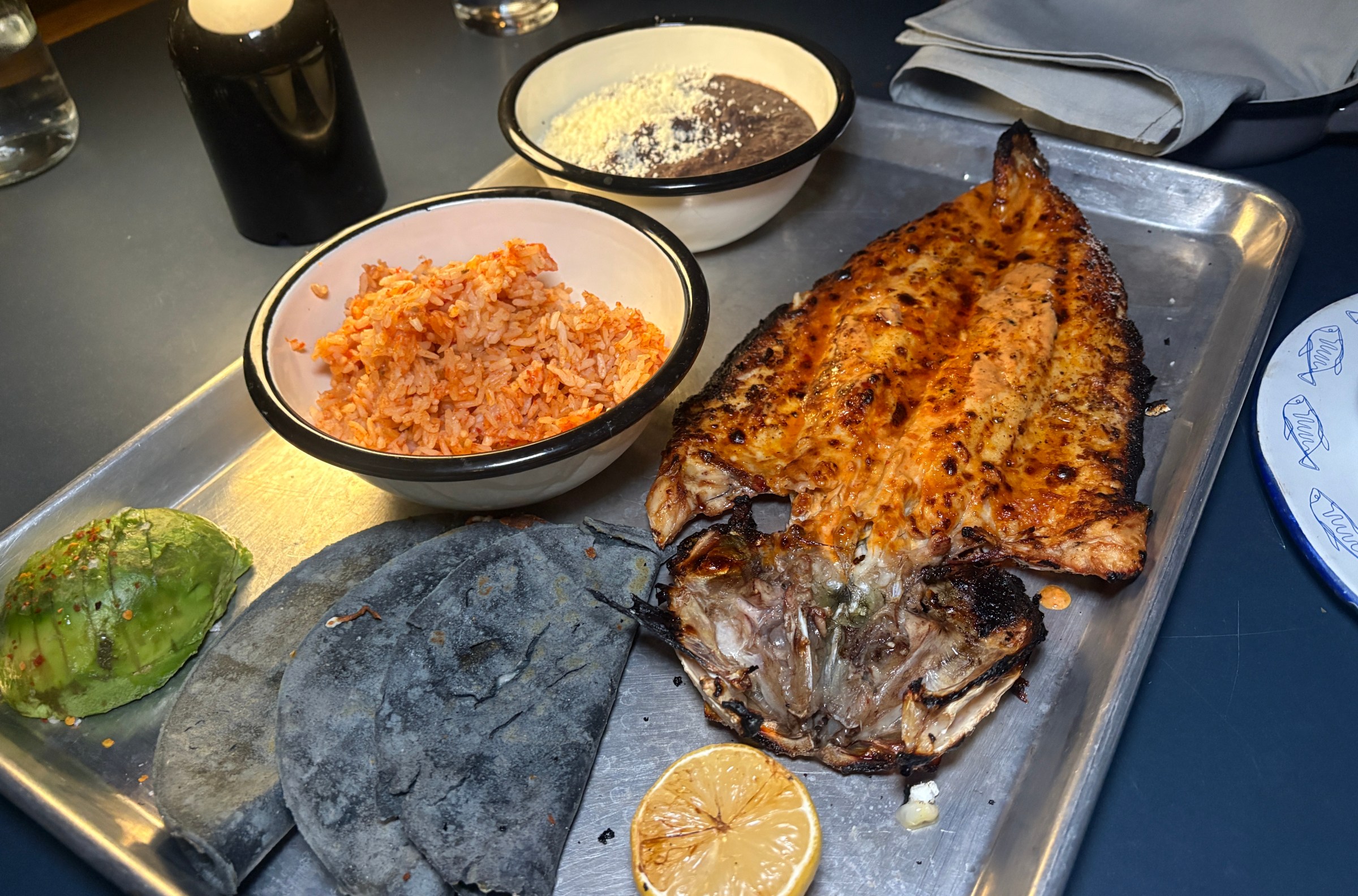 Whole charred branzino on a tray served with quesadillas, rice, and beans at Loreto.