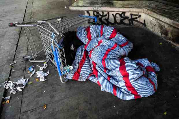 A homeless person sleeps across from Los Angeles City Hall where AHF's Housing Is A Human Right advocates wrap red ribbon around Los Angeles City Hall to symbolize how red tape prevents affordable housing on Tuesday, April 22, 2025. (Photo by Sarah Reingewirtz, Los Angeles Daily News/SCNG)