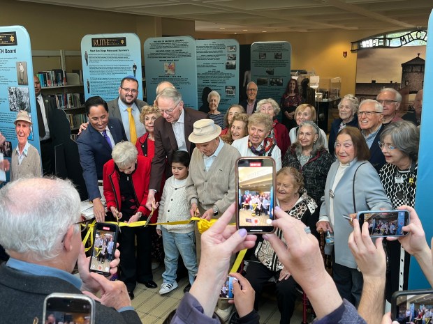 A group of Holocaust survivors and others cuts a yellow ribbon Jan. 12 to commemorate the new La Jolla exhibit "Remember Us The Holocaust." (Noah Lyons)