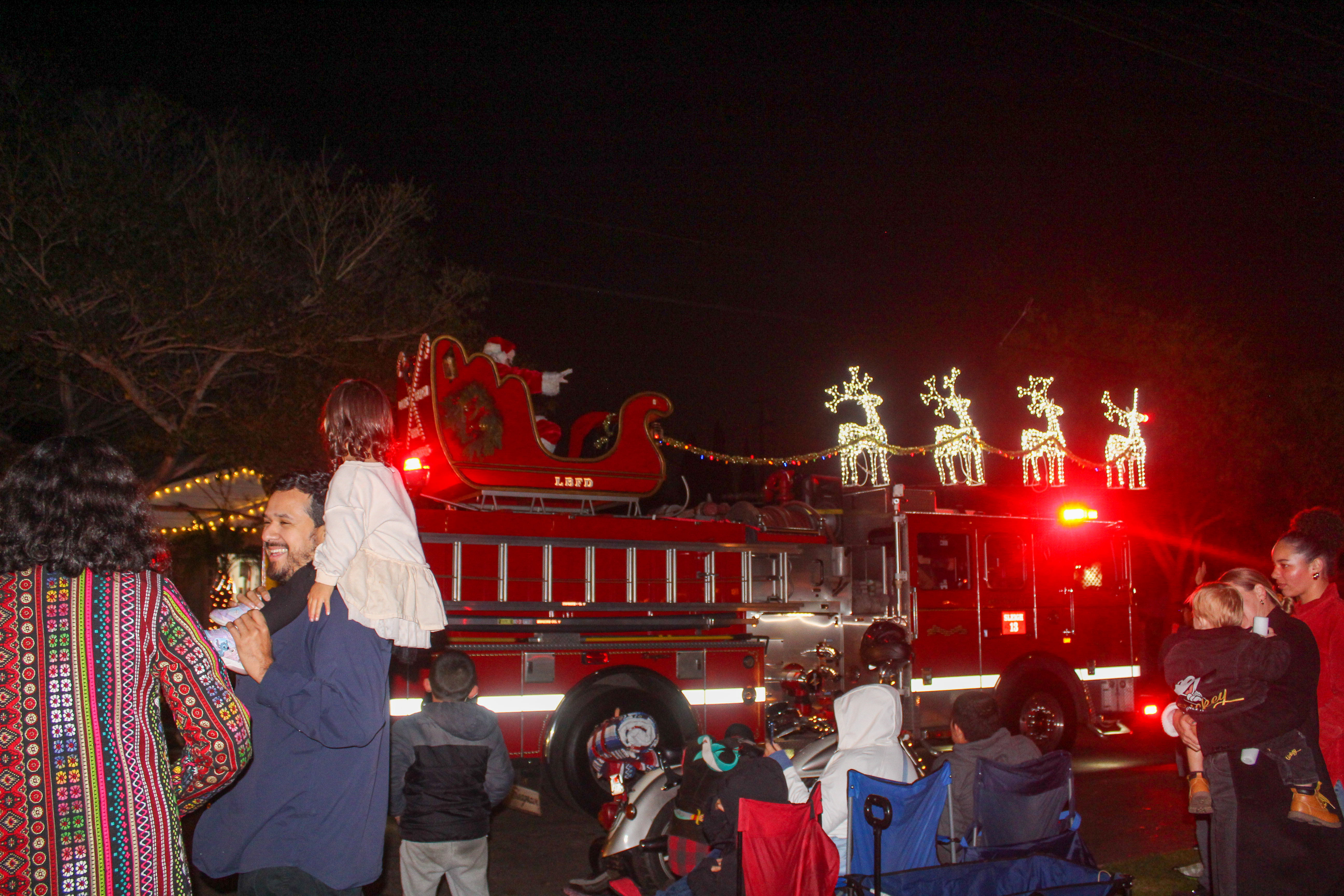 Santa Claus waves to the crowd from a sleigh on...