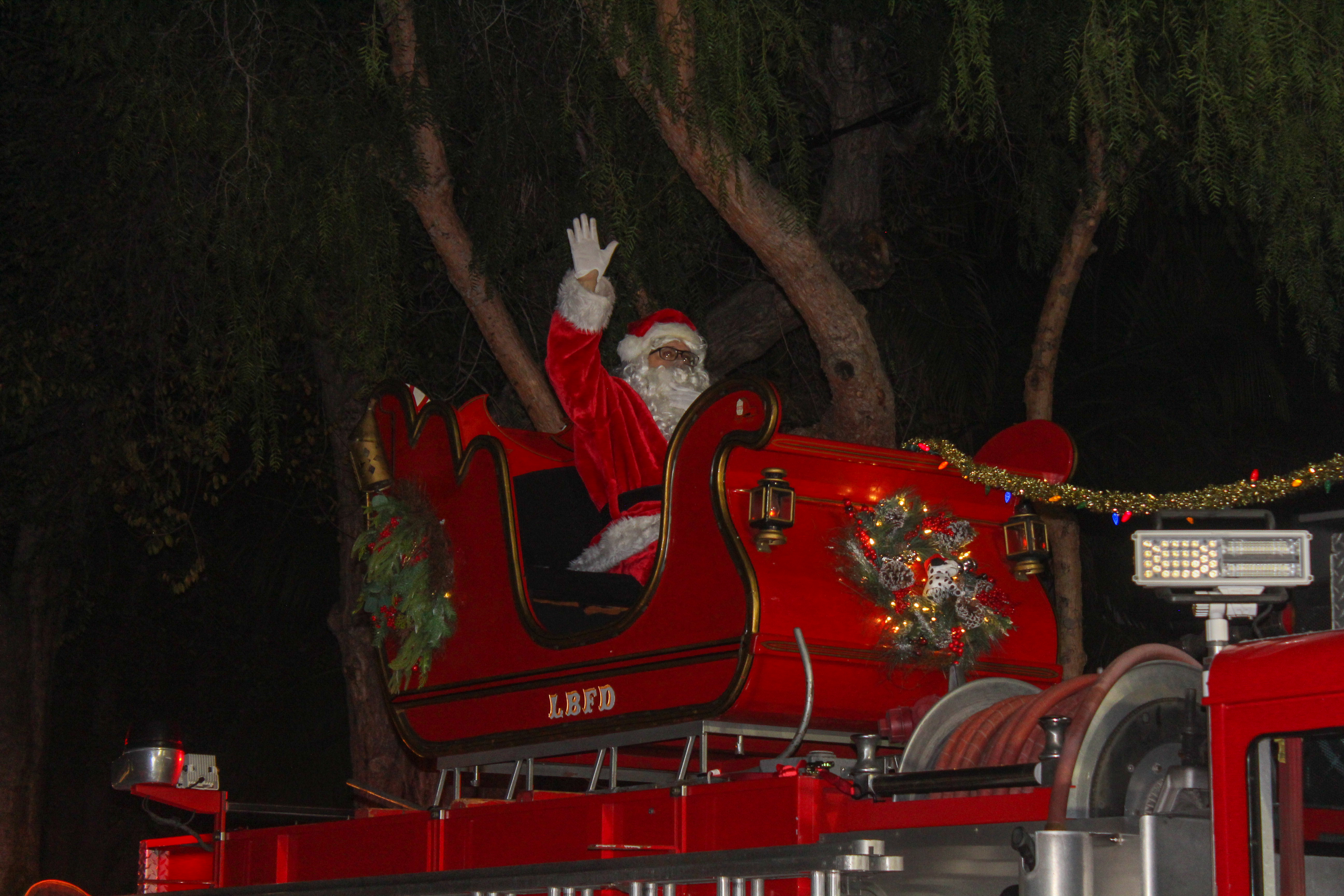 Santa Claus waves to the crowd from a sleigh on...
