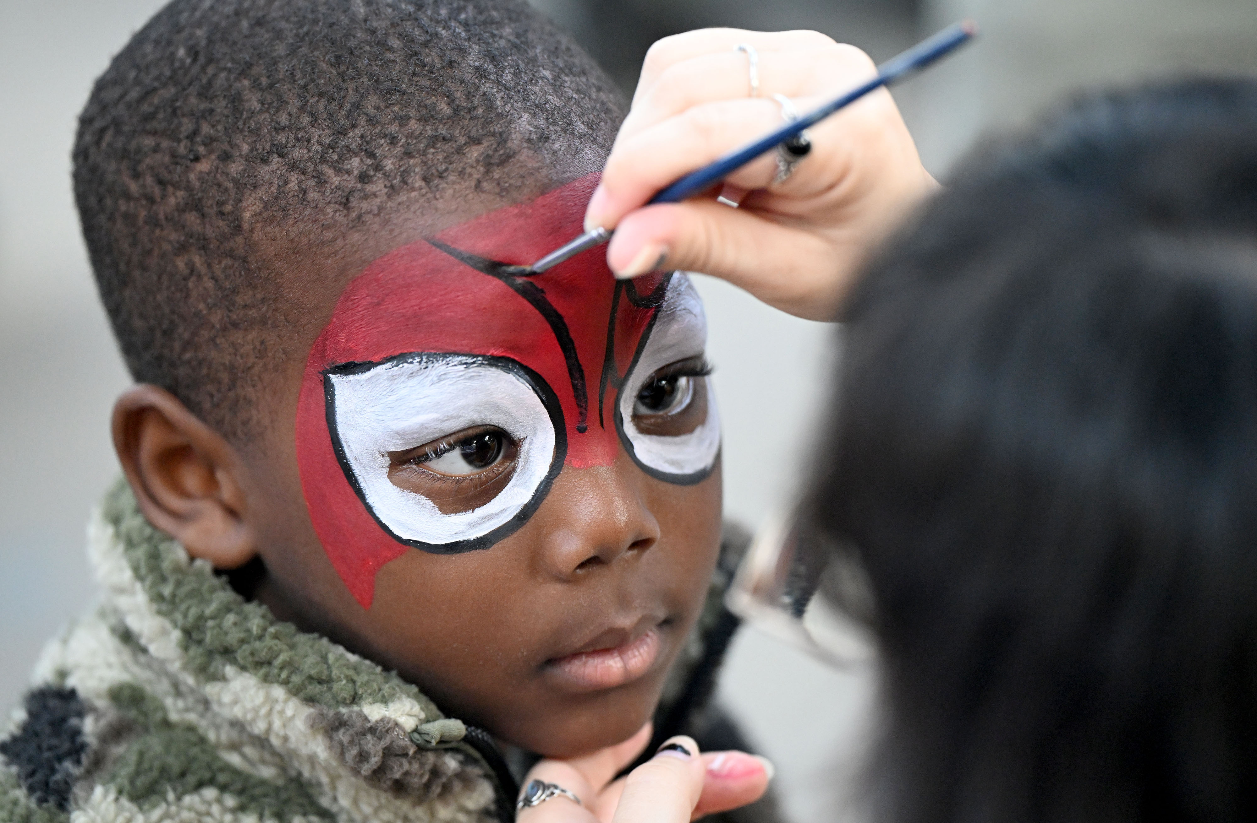 Dorian Harris, 4, has his face painted by Wendy Hurwit...