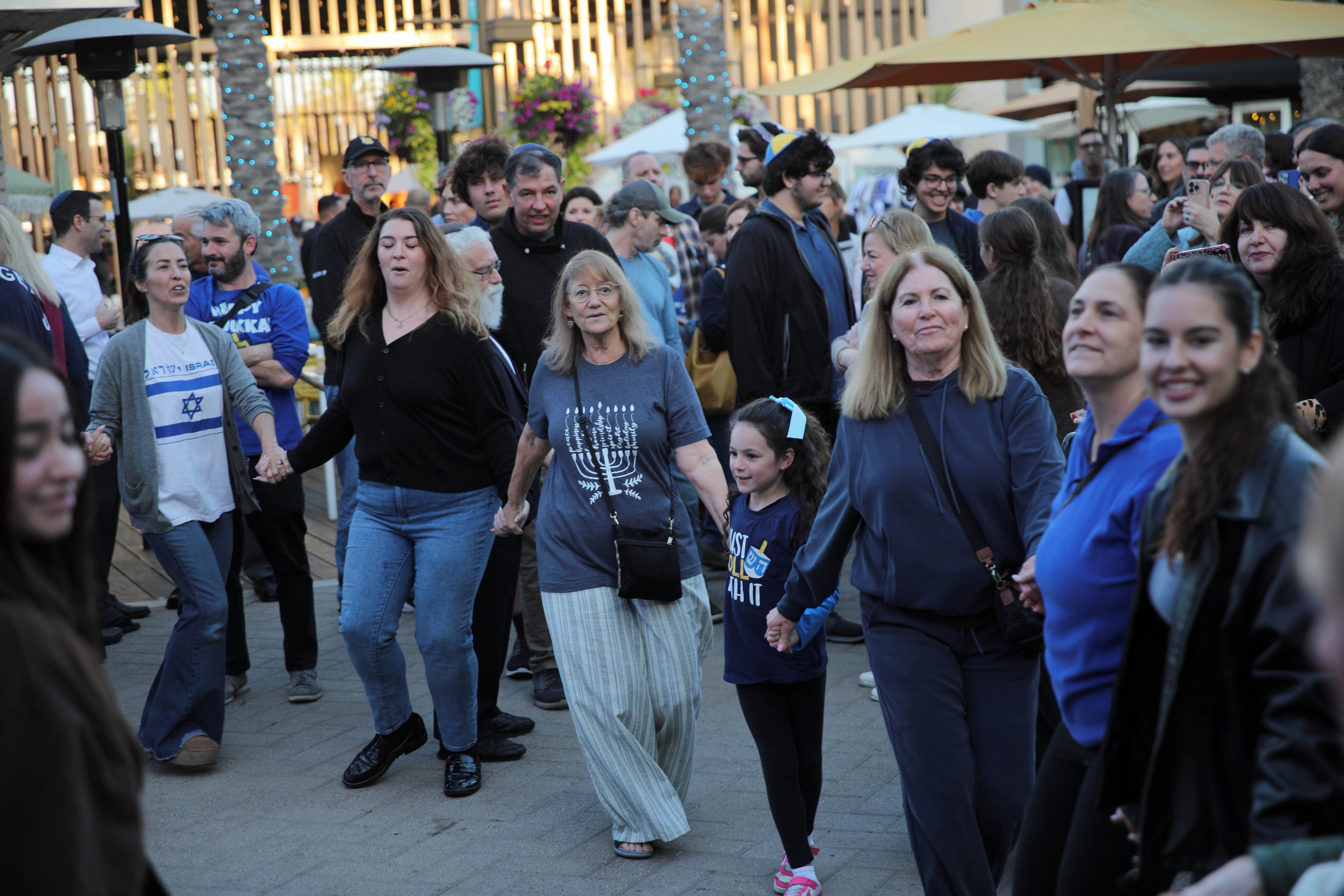 Celebrants dance at a Hanukkah menorah lighting event on Sunday,...