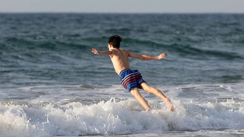 Boy plunges into the ocean at La Jolla Shores.