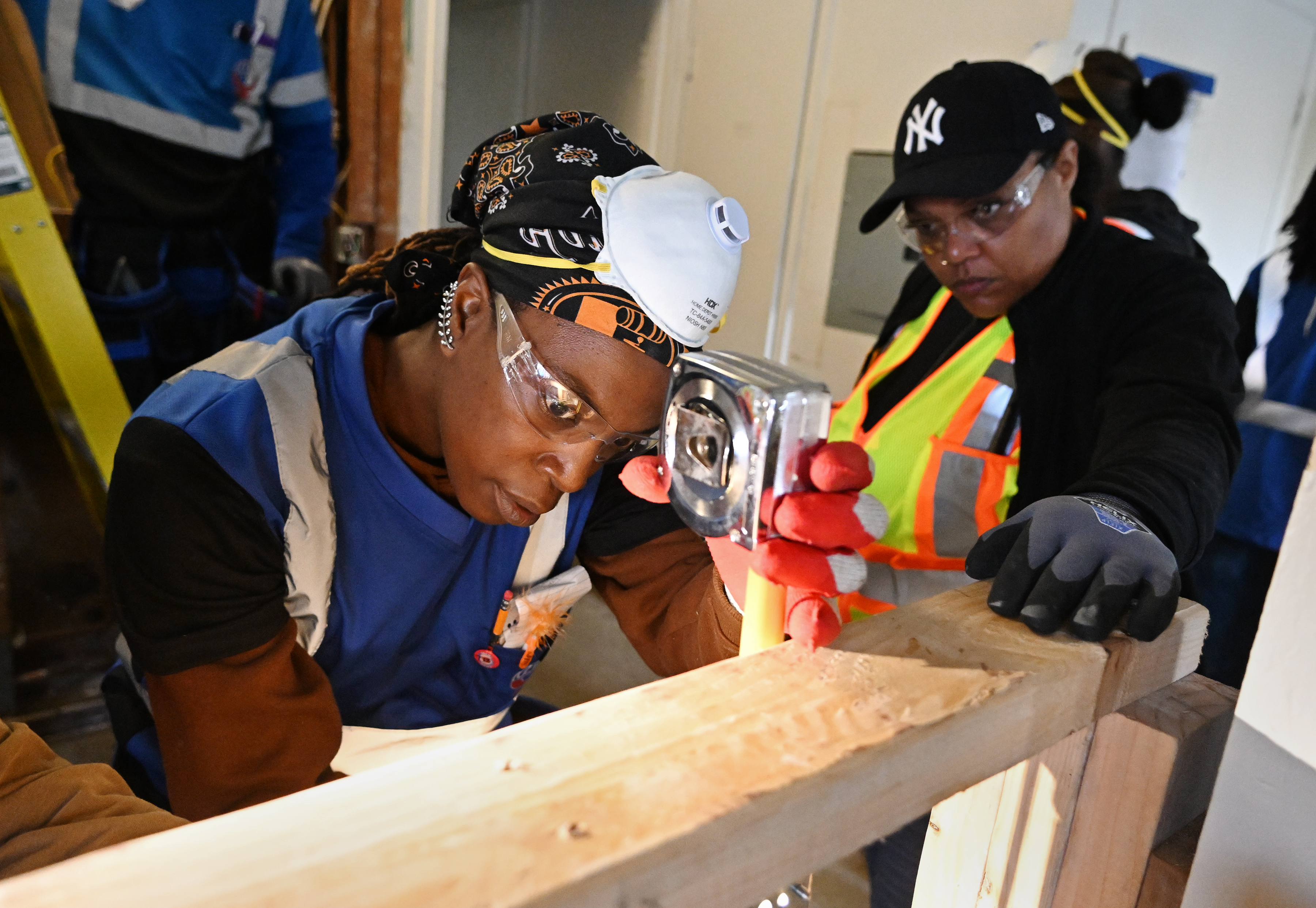 Tasharah Benjamin takes a measurement as Tatiana Williams watches during...