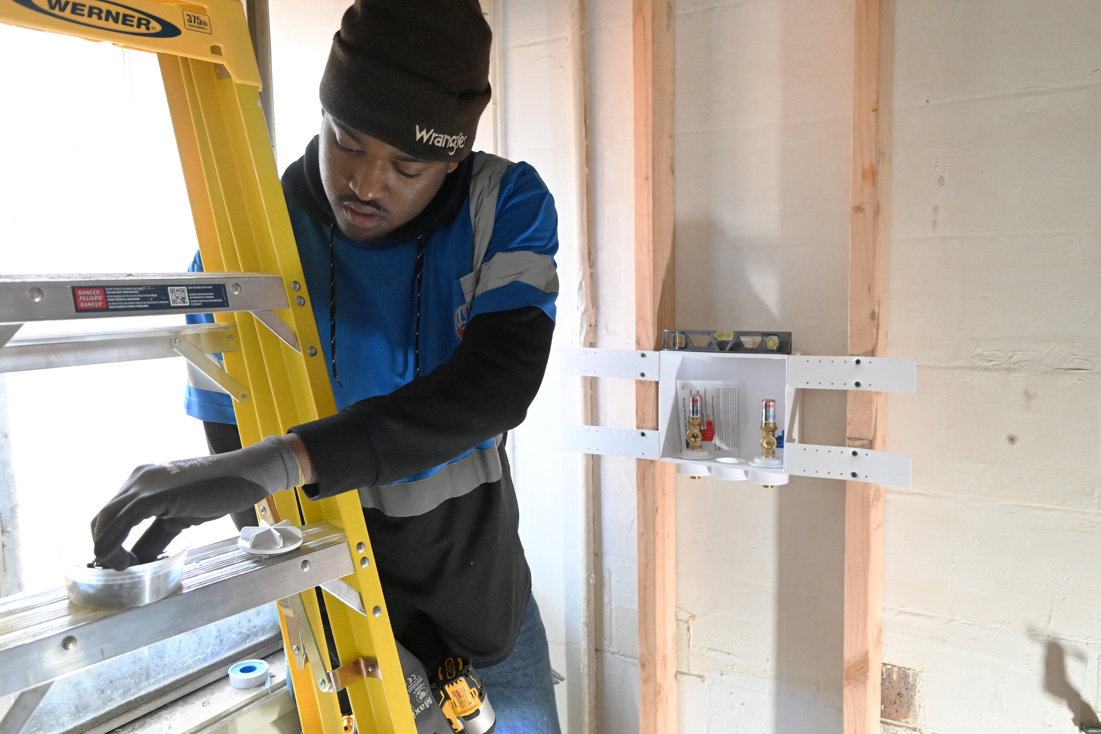 Trainee Jason Iles installs a washing machine outlet box in...