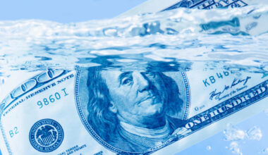 Image of a $100 bill floating in water with a sparkling blue hue