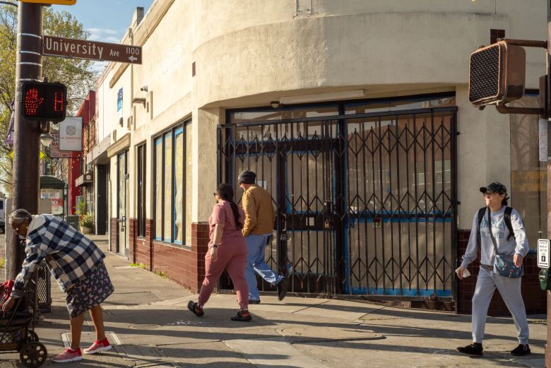 Several pedestrians walk past a vacant storefront