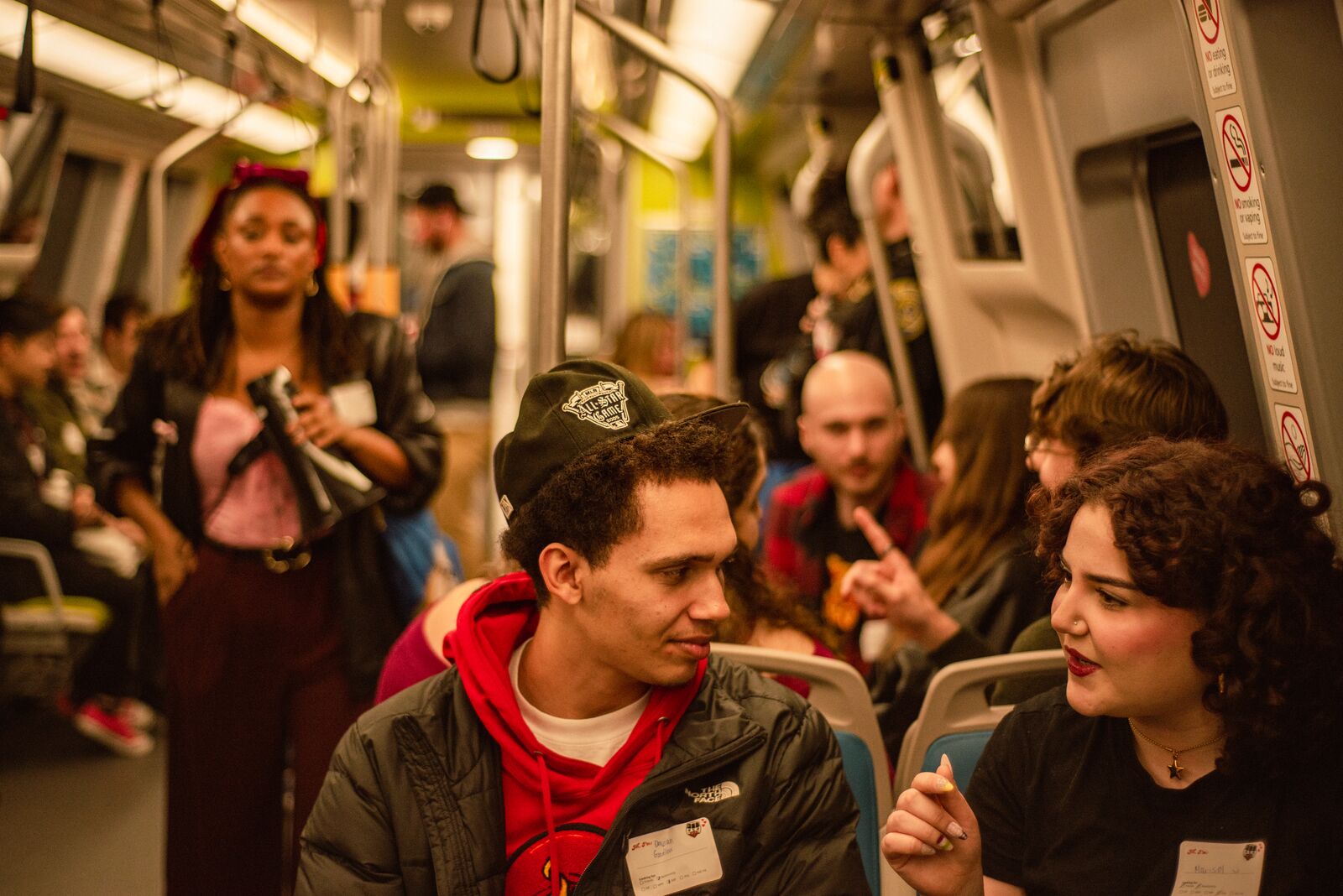 Two young people in intimate conversation on a populated BART train.