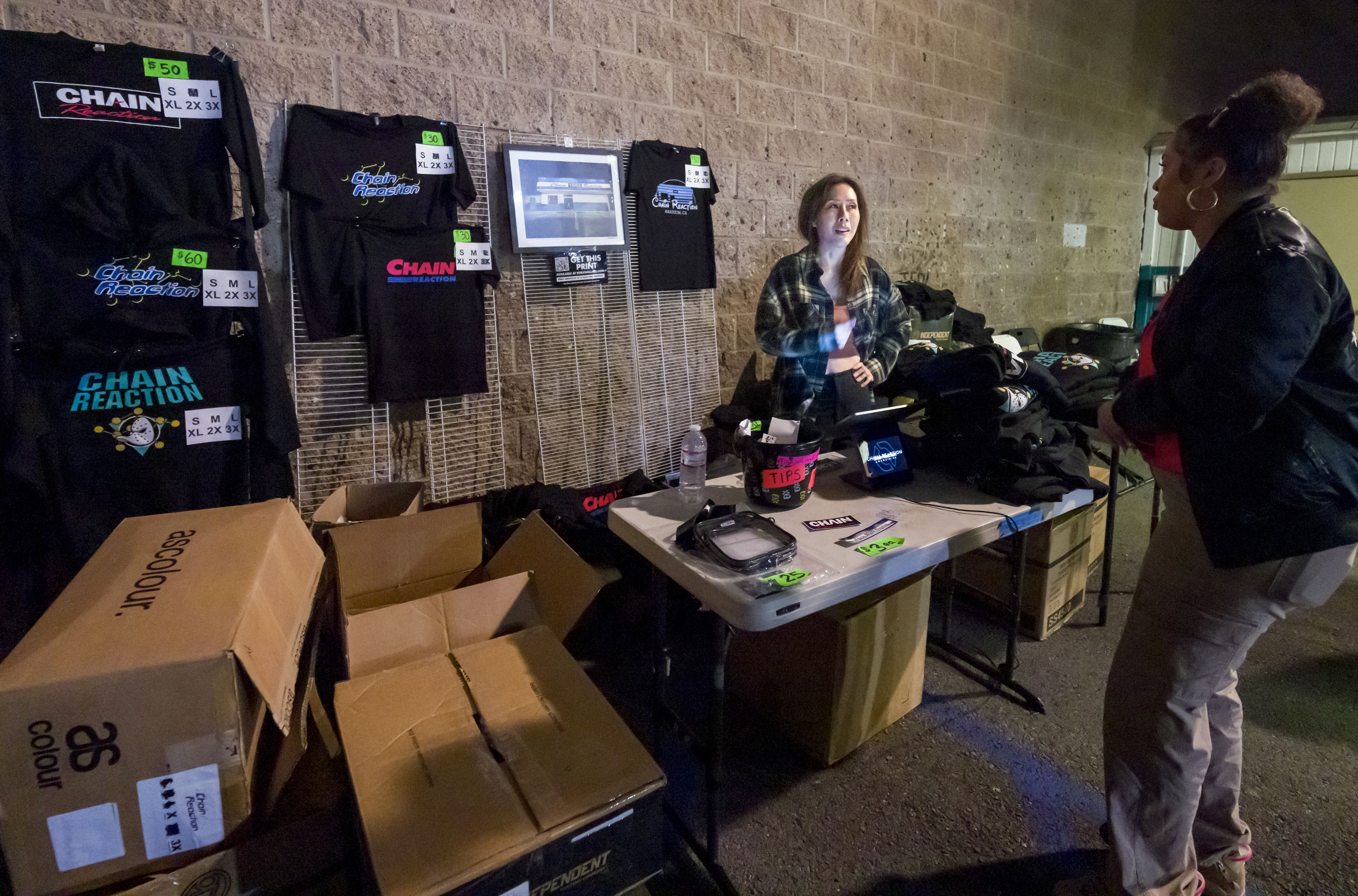 Lonnie Nguyen, left, sells Chain Reaction merch outside the venue...