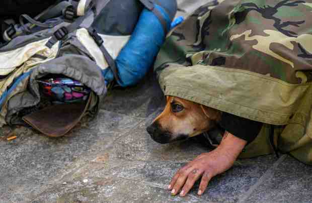 A man who only wanted to be identified as Damian, and his dog, Fish, are awoken at the Huntington Beach Pier Plaza Amphitheater during the early morning point in time count of homeless people on Tuesday, February 22, 2022. (Photo by Mindy Schauer, Orange County Register/SCNG)