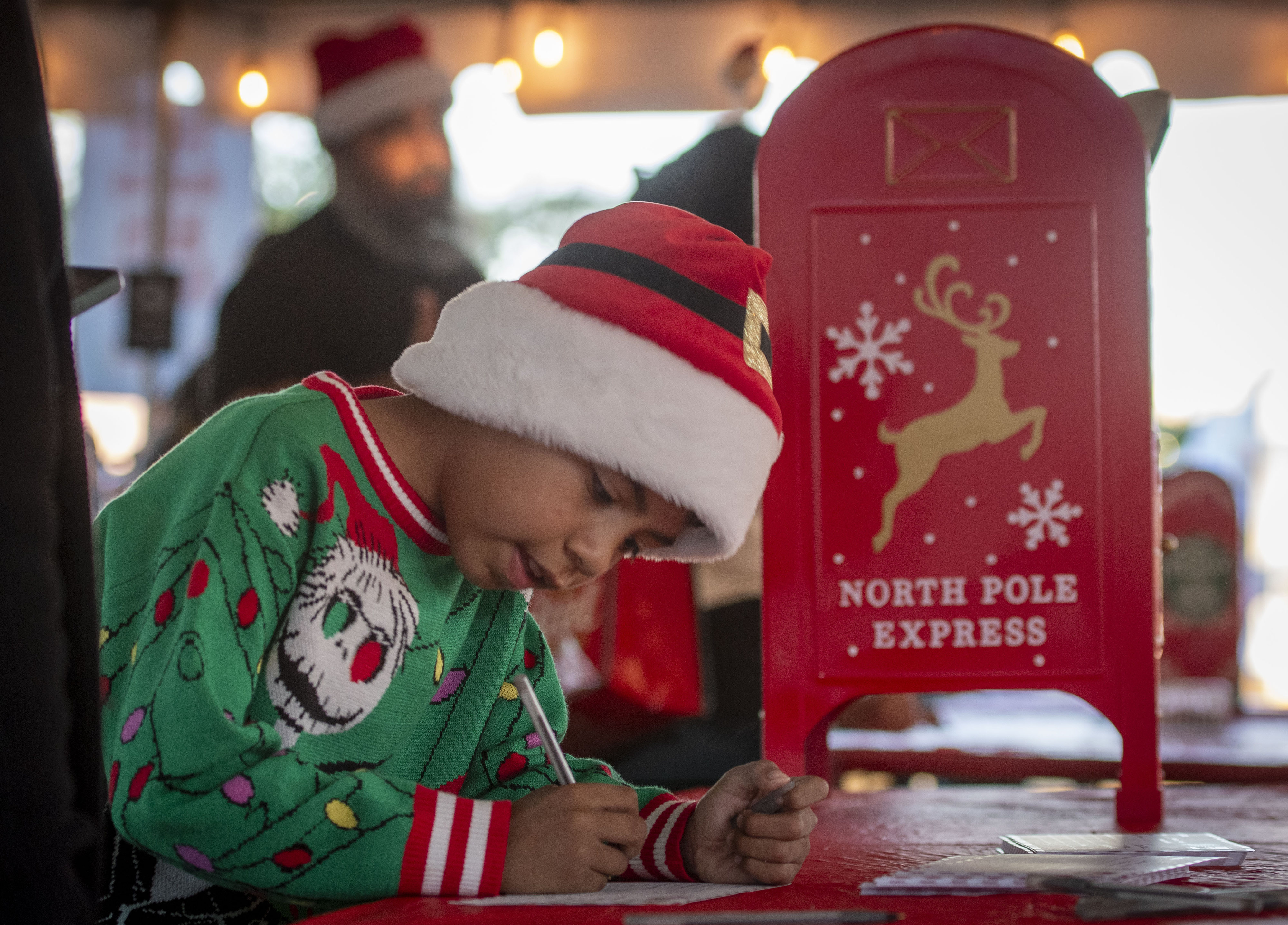 Felix Gonzalez, 8, writes a letter to Santa Saturday. Merrymakers...