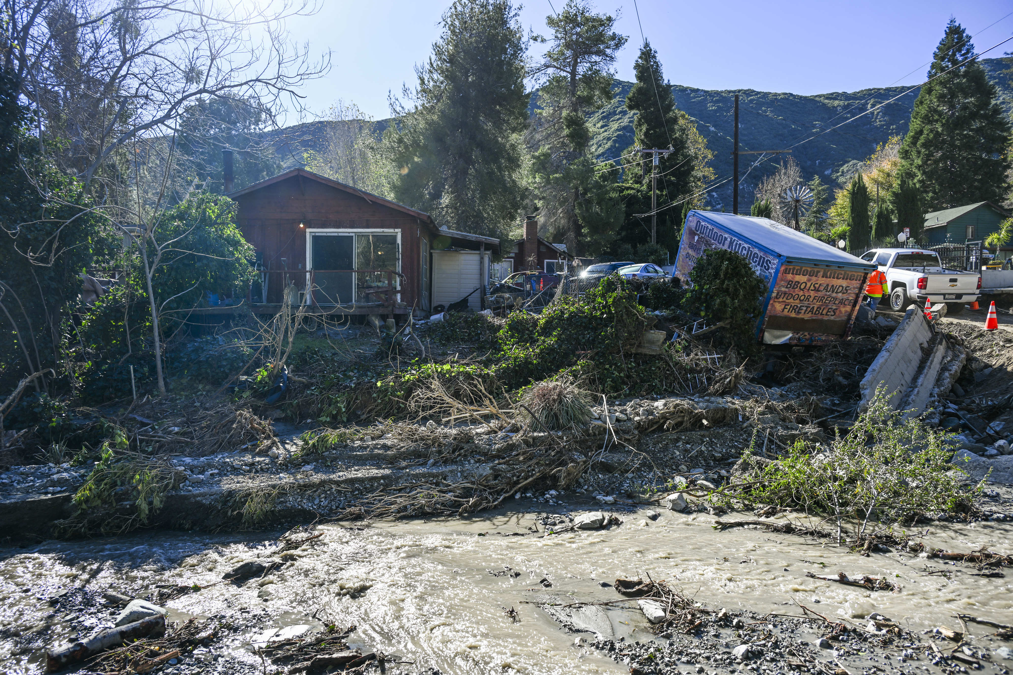 Property damage and debris line the damaged roadway and bridge...
