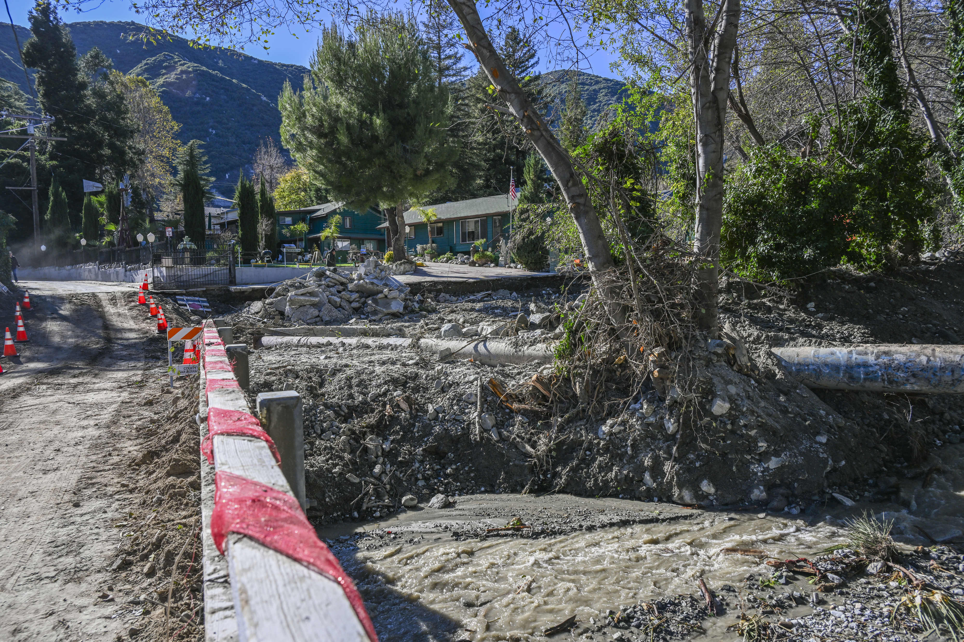 Property damage and debris line the damaged roadway and bridge...