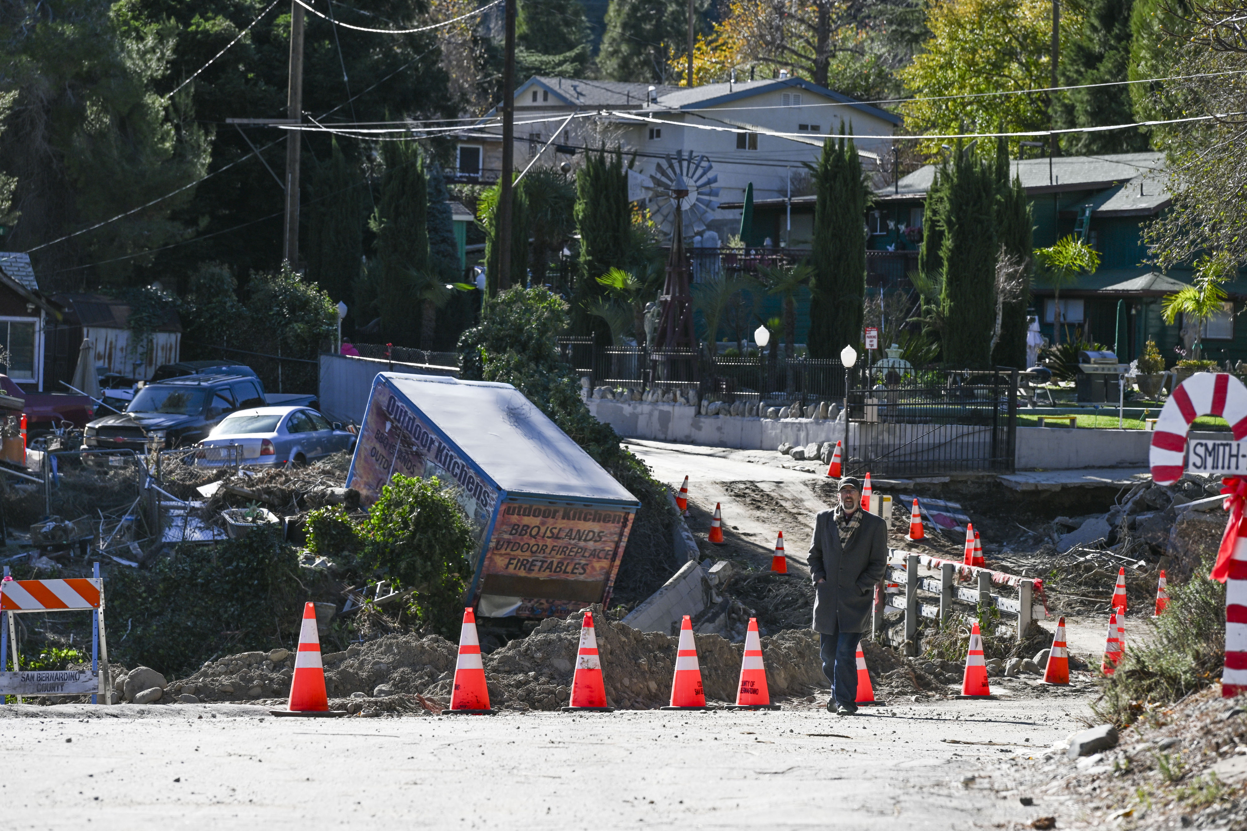 Property damage and debris line the damaged roadway and bridge...